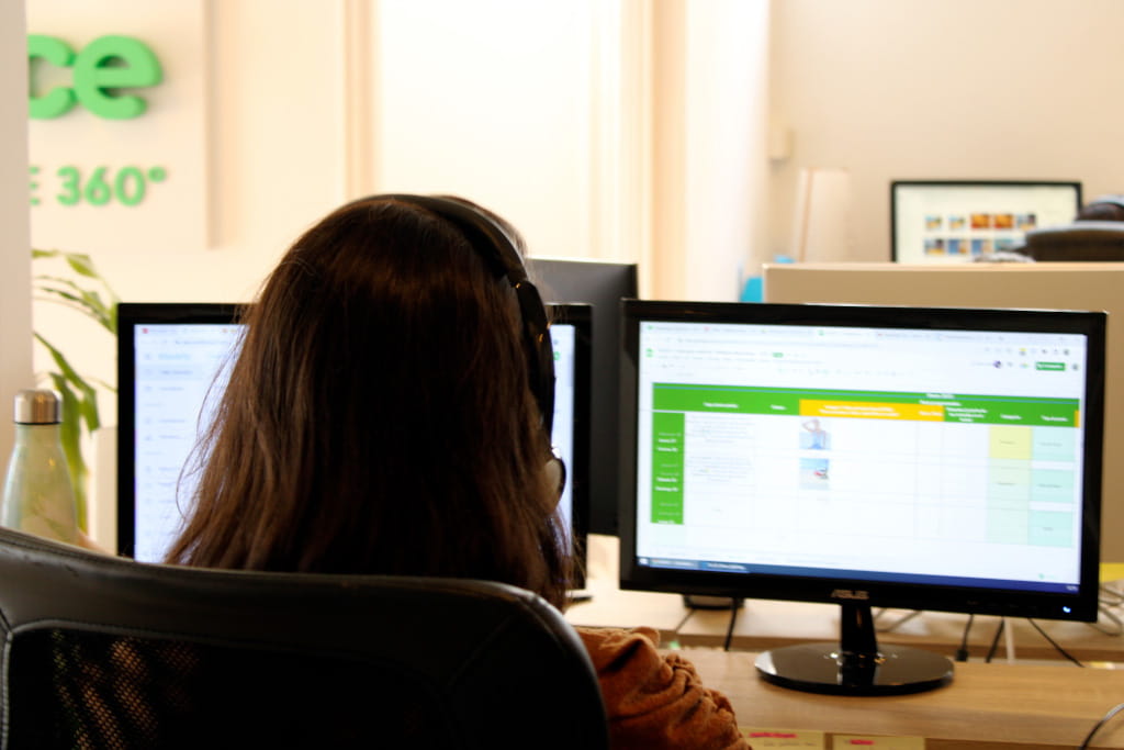 Utente al computer con cuffie e schermo aperto su foglio di calcolo.