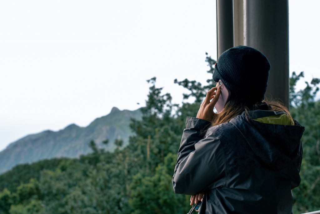 Persona in giacca e cuffia guarda le montagne e gli alberi a Tenerife.