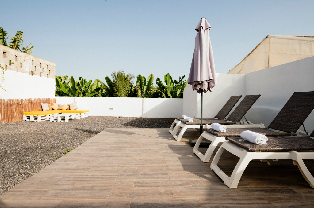 Lettini e ombrellone su una terrazza di Tenerife con piante sullo sfondo.