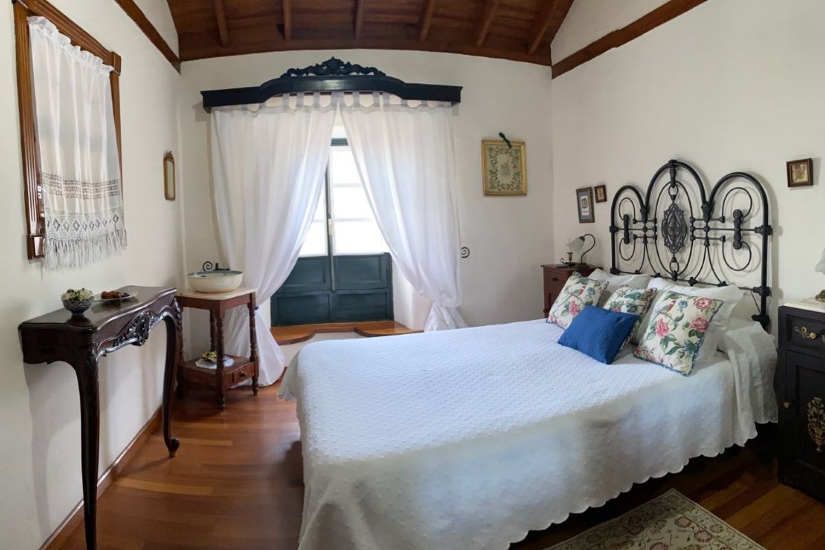 Camera da letto con letto matrimoniale, cuscini floreali e tenda bianca a Tenerife.