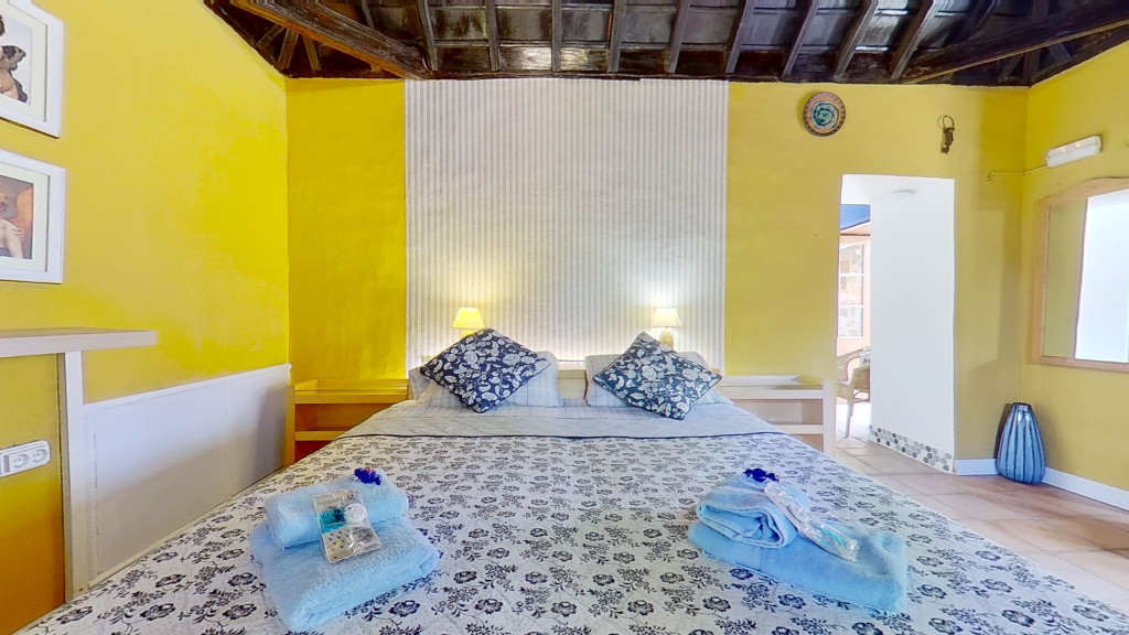 Camera da letto con pareti gialle e letto matrimoniale a Tenerife.