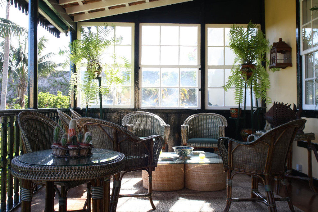 Veranda con sedie di vimini e tavolo di vetro, piante da interno a Tenerife.