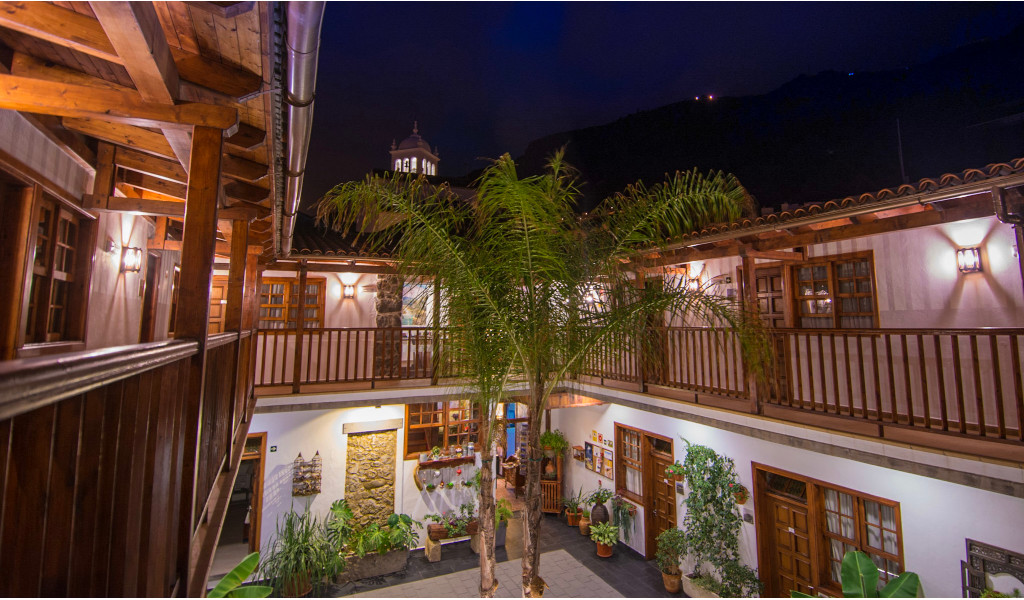 Cortile interno con balconi in legno e vegetazione a Tenerife di notte.