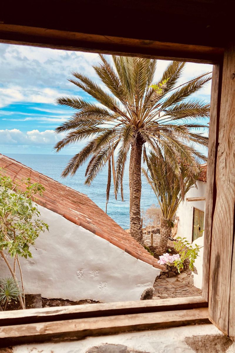 Vista mare e palme dalla finestra su una casa tradizionale a Tenerife.