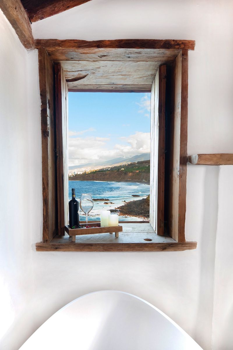 Finestra con vista sul mare a Tenerife, bottiglia e bicchiere su un vassoio di legno.