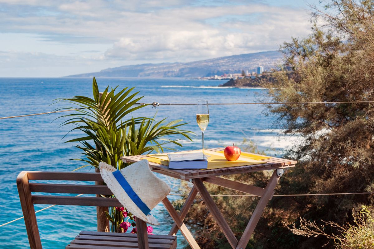 Tavolo con bicchiere di vino, mela e libro vista mare a Tenerife.