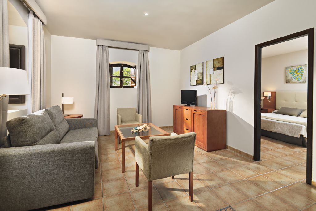 Soggiorno con divano, tavolino, sedie e TV, vista camera da letto, Tenerife.