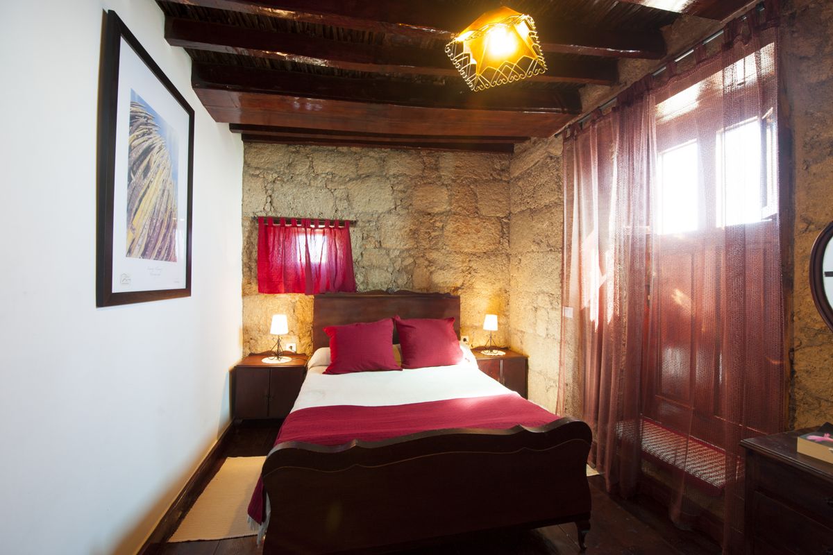 Camera da letto con letto matrimoniale, travi in legno, luci soffuse, a Tenerife.