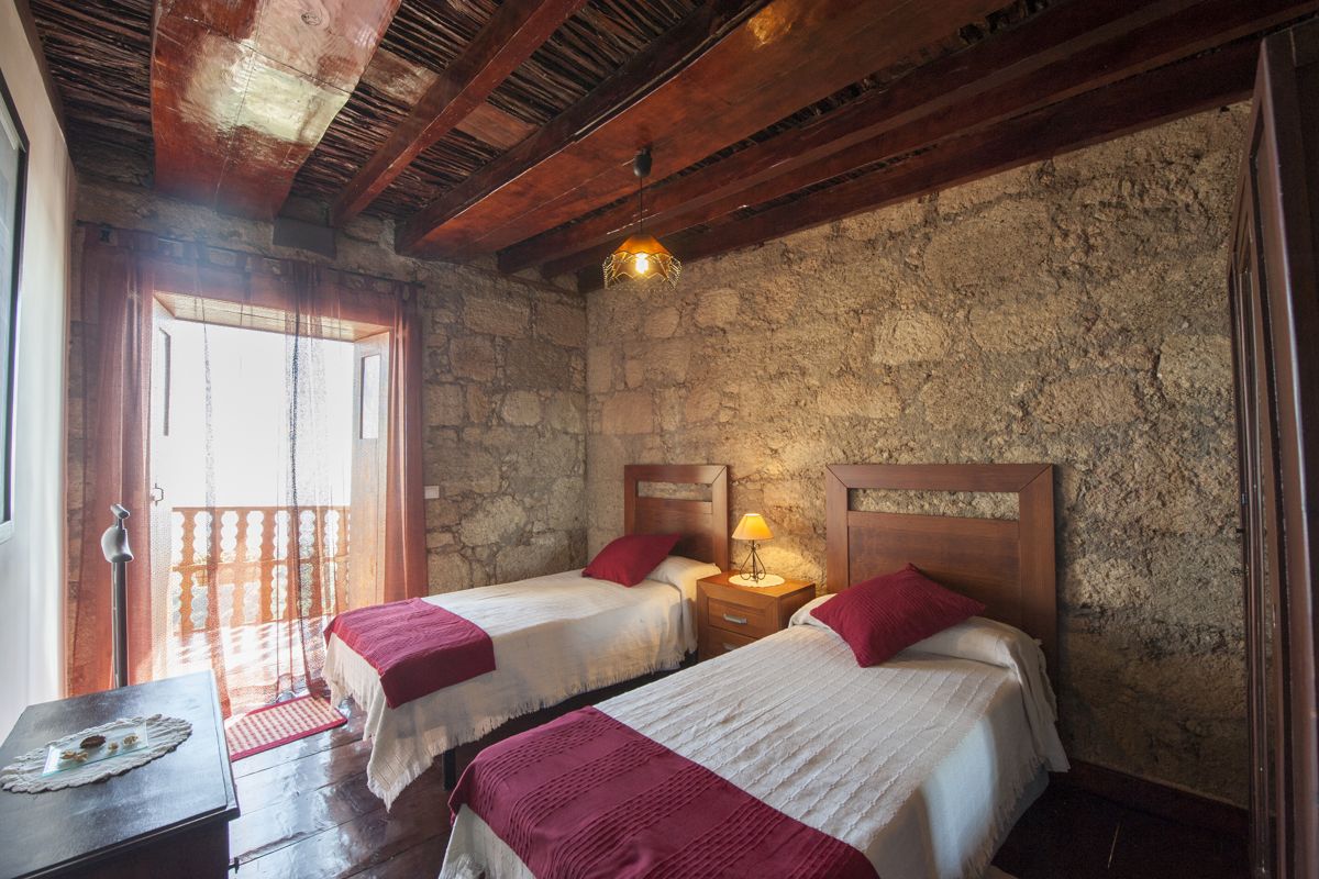Due letti singoli in una stanza con pareti di pietra e soffitto in legno a Tenerife.