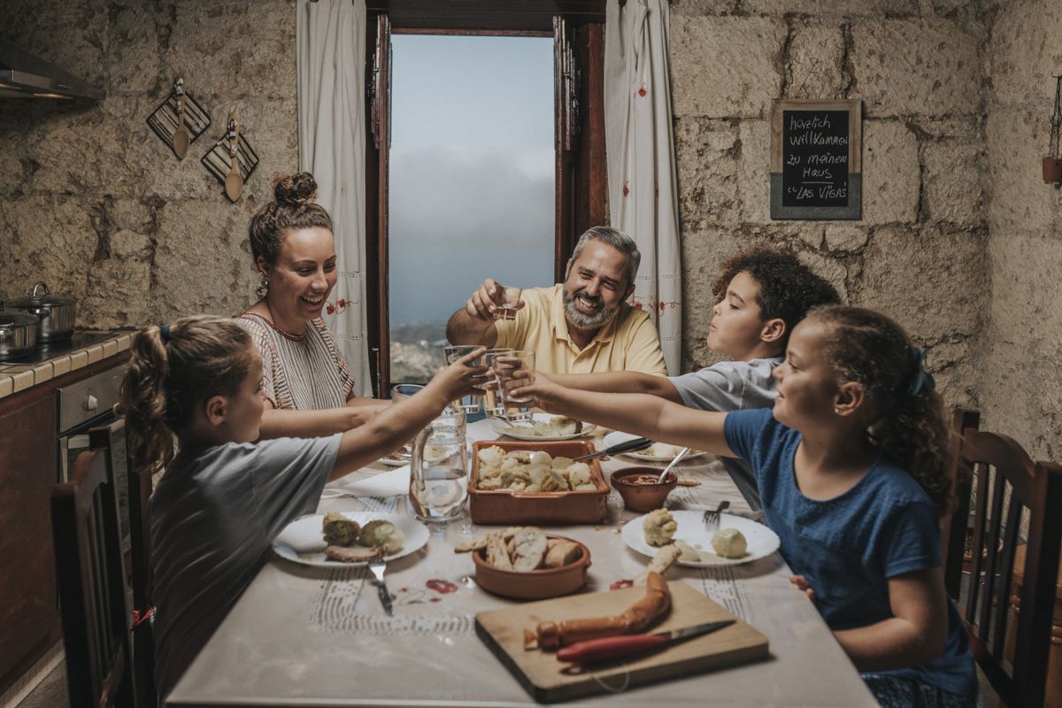 Famiglia brinda a cena con vista sul mare di Tenerife. Scritta sulla lavagna: herzlich willkommen zu meinem Haus.