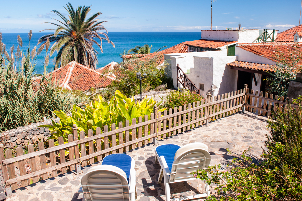 Terrazza soleggiata con lettini, palme e vista sull'oceano a Tenerife.