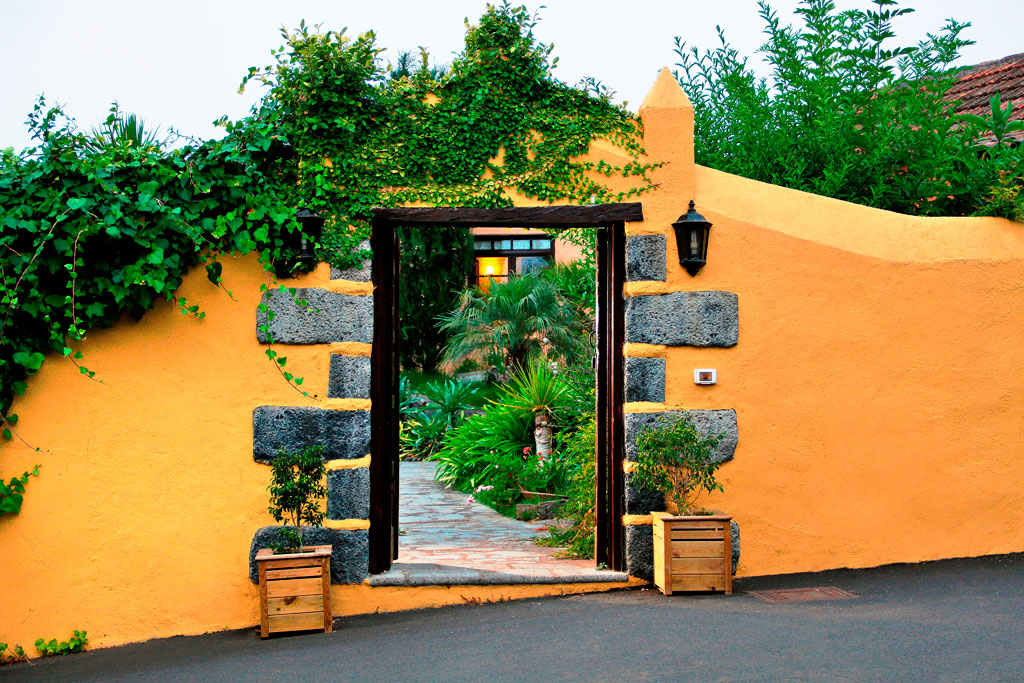 Giardino verde con muro in pietra e intonaco arancione a Tenerife.