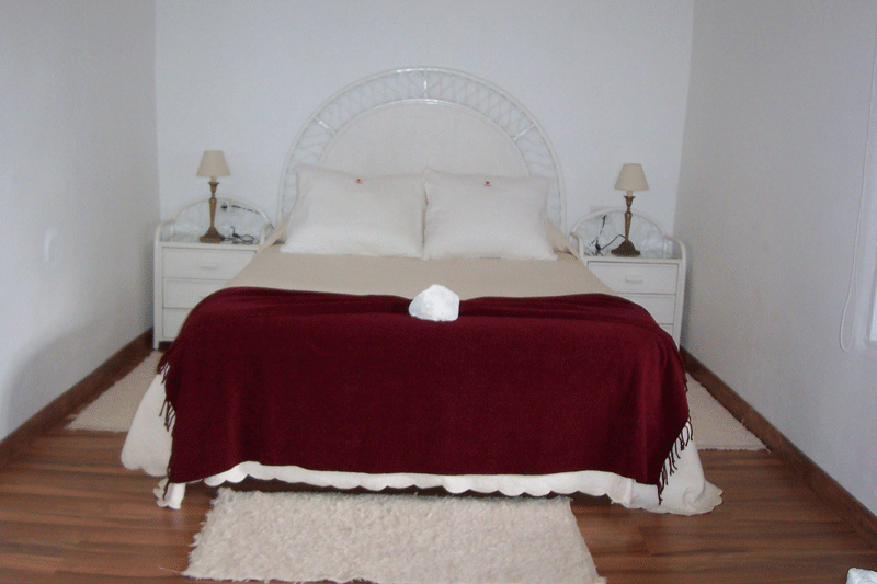 Letto matrimoniale con coperta rossa e due comodini nel luogo di Tenerife.