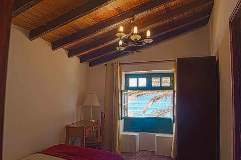 Camera con soffitto di legno e finestra vista mare a Tenerife.
