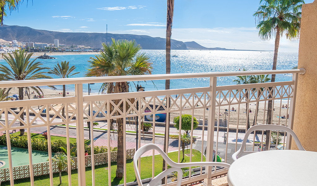 Vista dal balcone con palme e spiaggia de Los Cristianos a Tenerife.