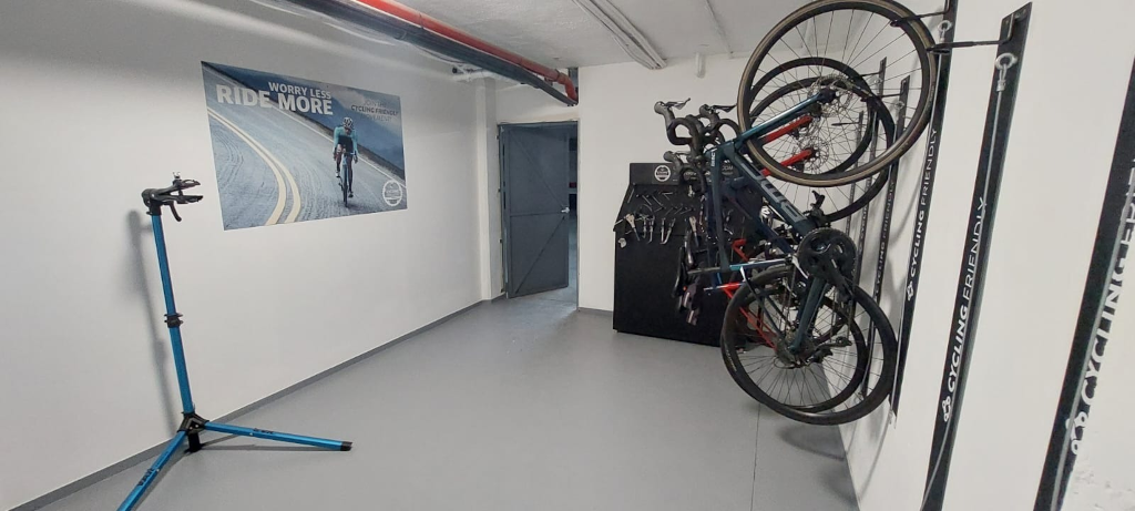 Laboratorio ciclistico con biciclette appese a parete e cartello Worry less, ride more.