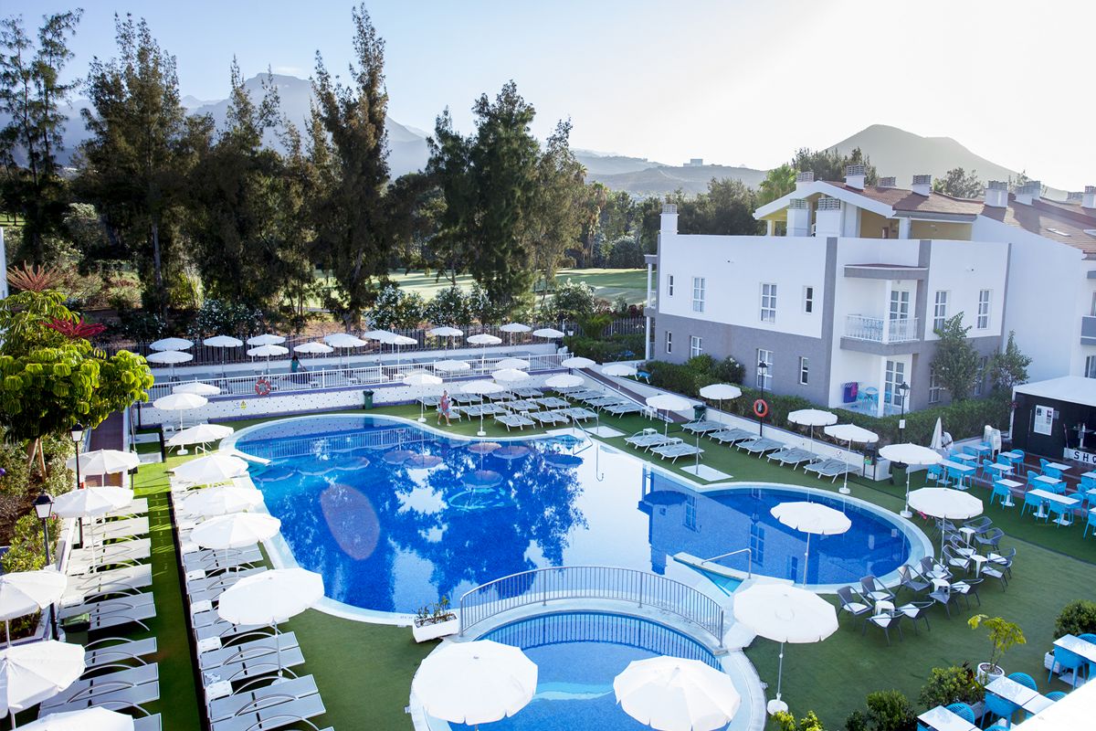 Piscina all'aperto con lettini e ombrelloni bianchi ad Adeje, Tenerife.