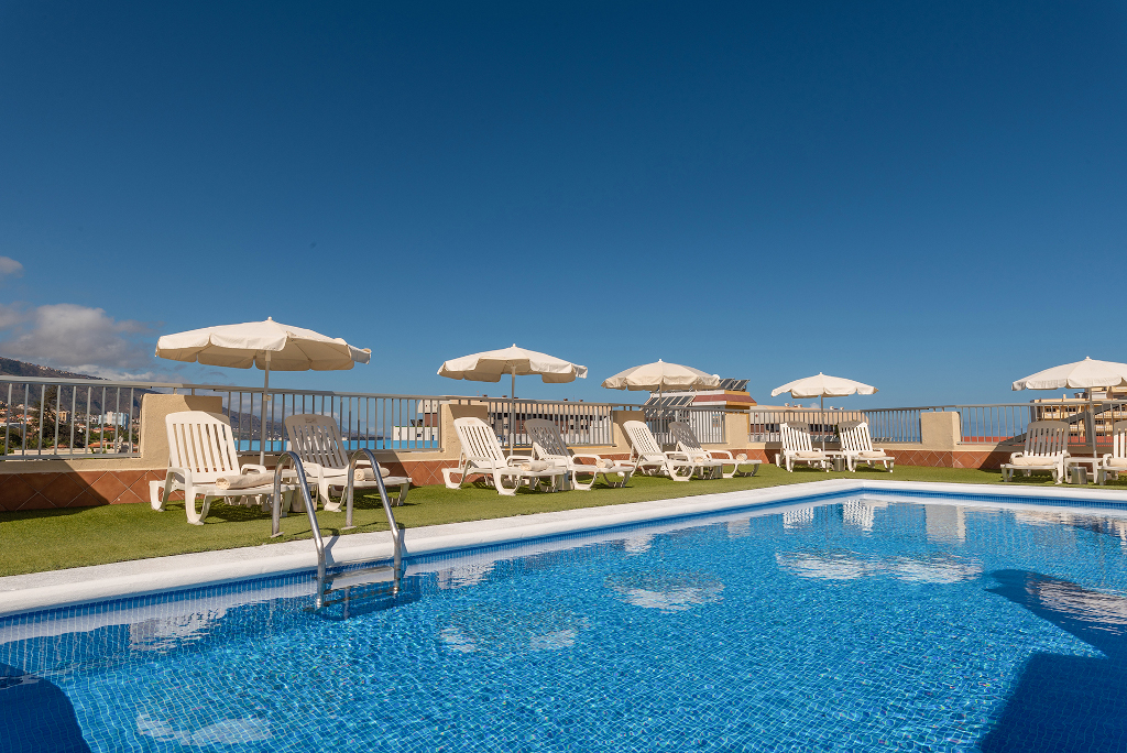 Piscina con lettini e ombrelloni sotto il cielo azzurro a Tenerife.