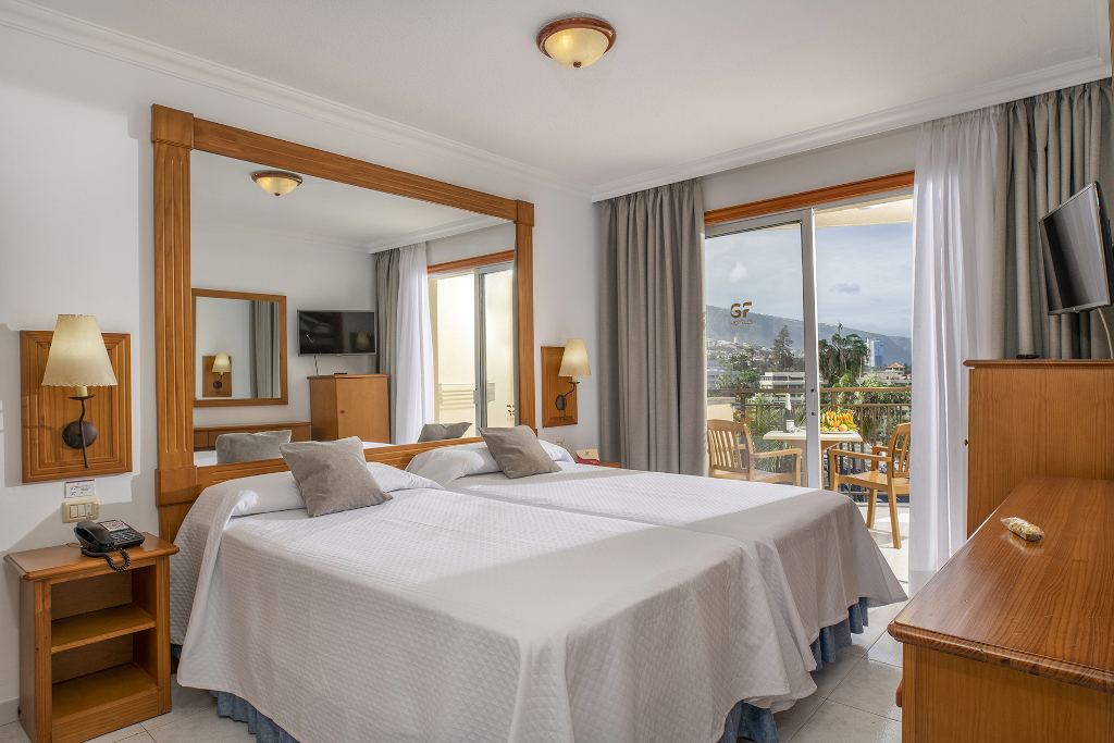 Camera d'albergo con letto matrimoniale, TV e balcone con vista a Tenerife.