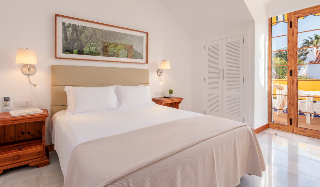 Camera da letto luminosa con letto matrimoniale a Tenerife, porta finestra aperta su terrazza.