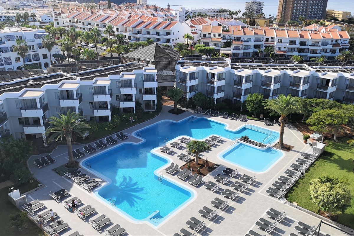 Piscina all'aperto con lettini e palme a Costa Adeje, Tenerife.