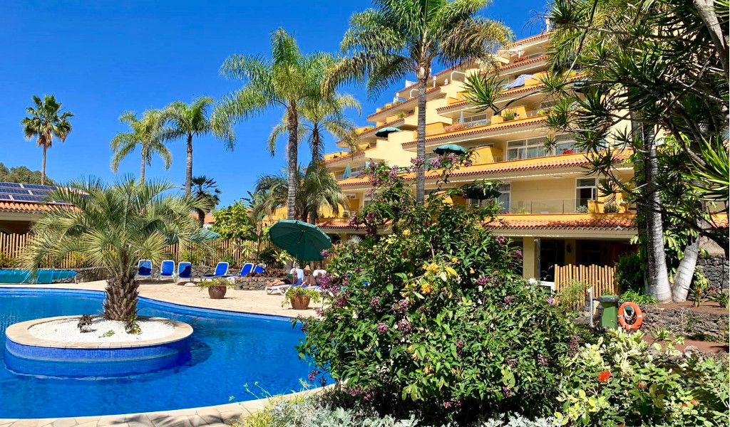 Piscina e giardino con palme davanti a un hotel a Tenerife.