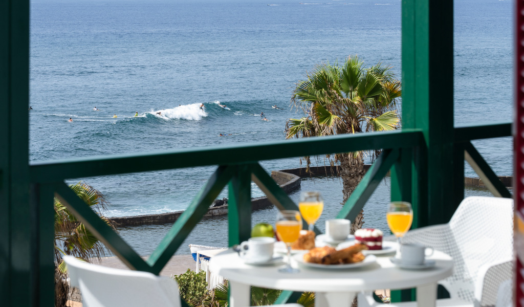 Colazione su balcone con vista mare e surfisti a Playa de las Américas, Tenerife.