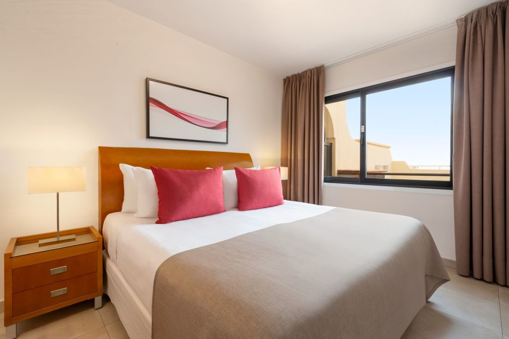 Camera da letto con letto matrimoniale, cuscini rosa, quadro e finestra a Tenerife.