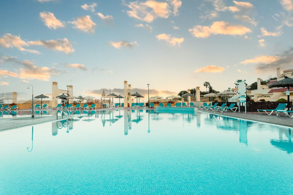 Piscina all'aperto al tramonto con lettini a Costa Adeje, Tenerife.
