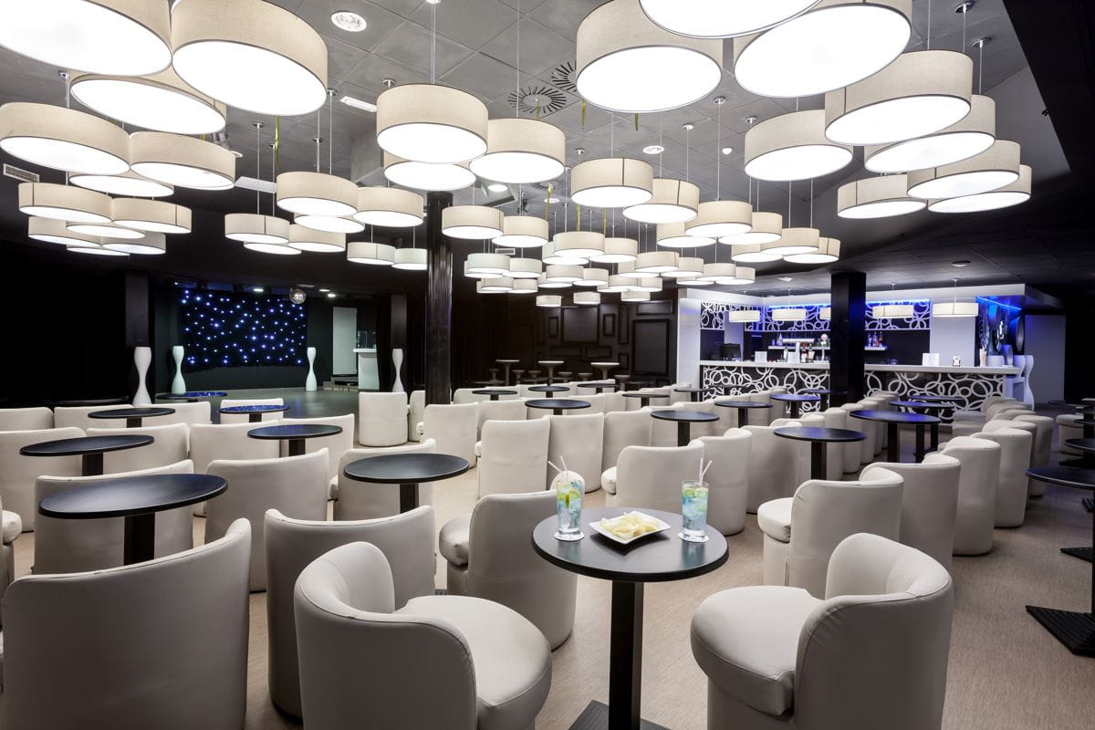 Sala lounge con sedie bianche e tavoli, illuminata da lampade rotonde, Tenerife.