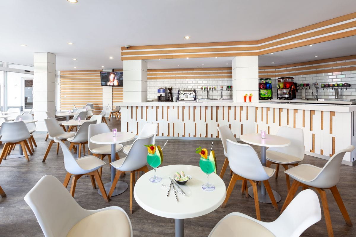 Interno moderno di un bar a Tenerife con sedie bianche e drink colorati su tavoli.