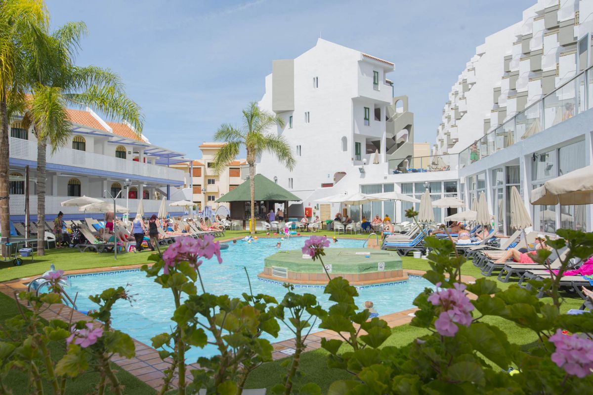 Piscina del resort a Playa de las Américas, Tenerife, con persone che si rilassano.