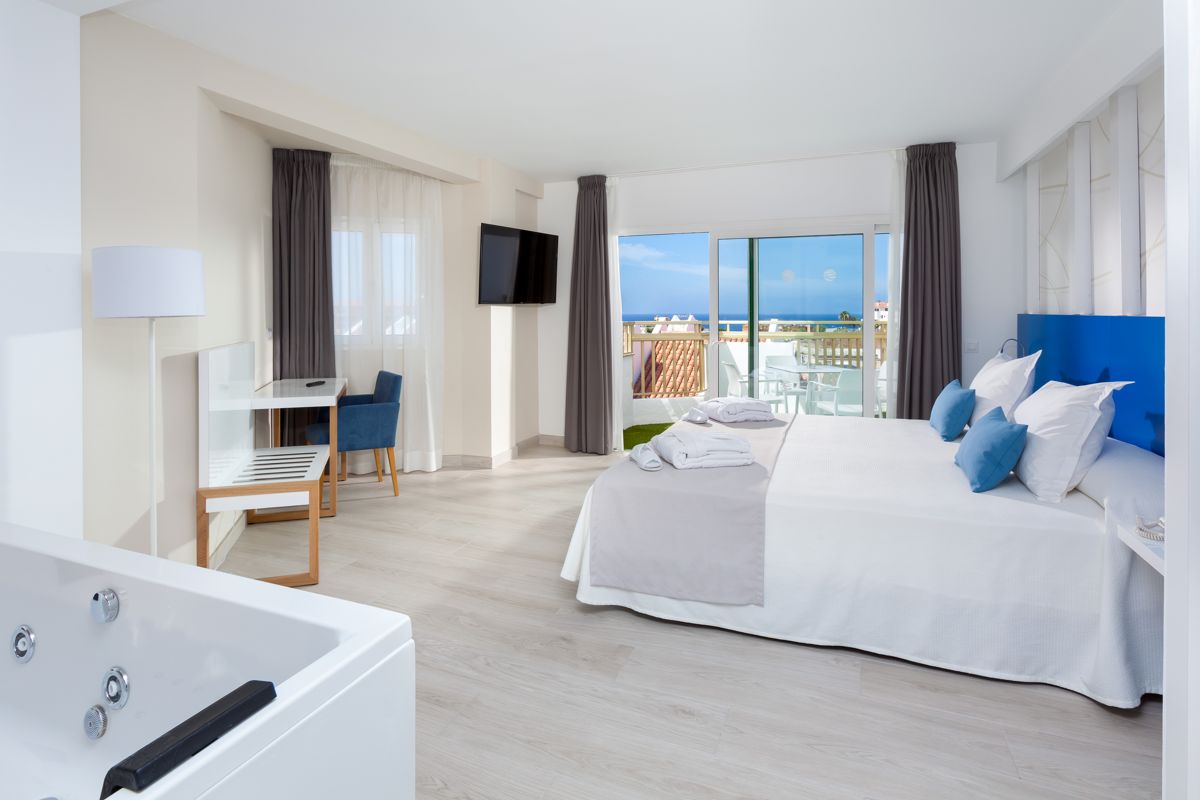 Camera da letto con jacuzzi, balcone vista mare a Tenerife, TV e divano.