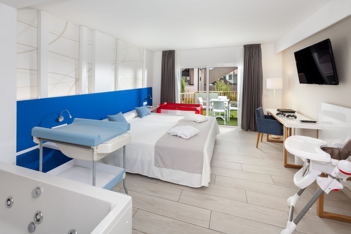 Camera d'hotel a Tenerife con lettino, scrivania e balcone vista giardino.