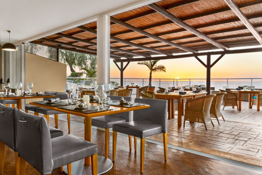 Ristorante con tavoli apparecchiati presso una terrazza con vista sul tramonto a Tenerife.