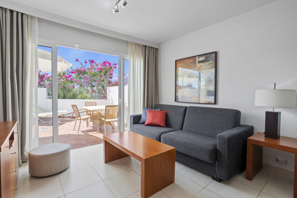 Soggiorno con divano grigio e terrazza con fiori a Tenerife.
