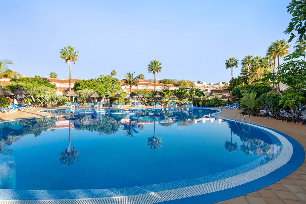 Piscina circondata da lettini e palme a Costa Adeje, Tenerife.