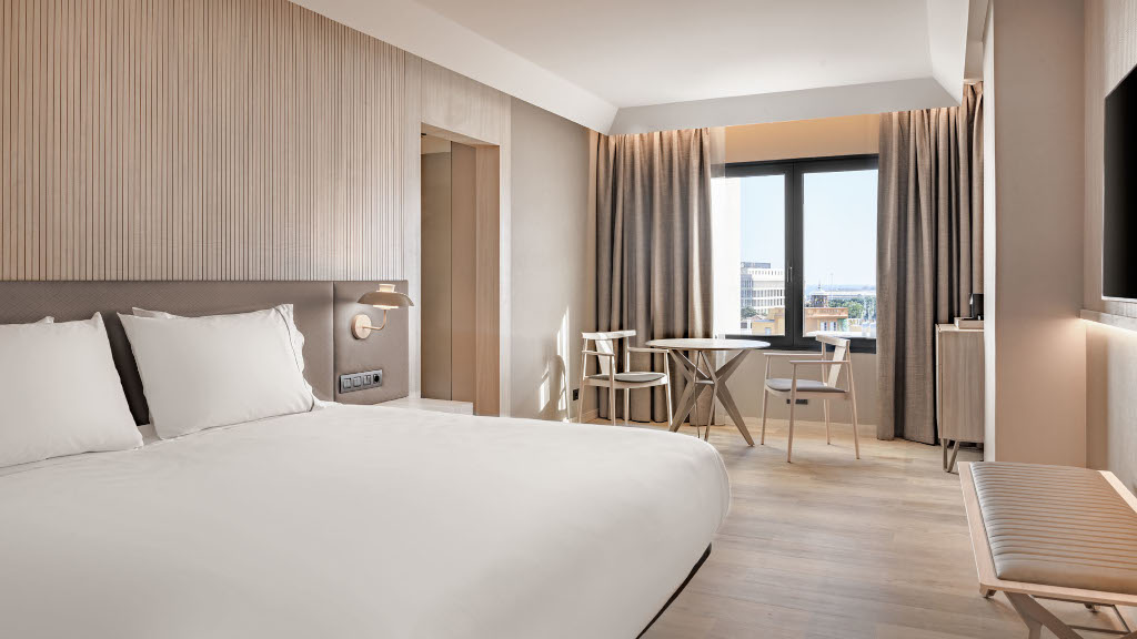 Camera da letto moderna con letto matrimoniale e tavolo, finestra con vista su Tenerife.