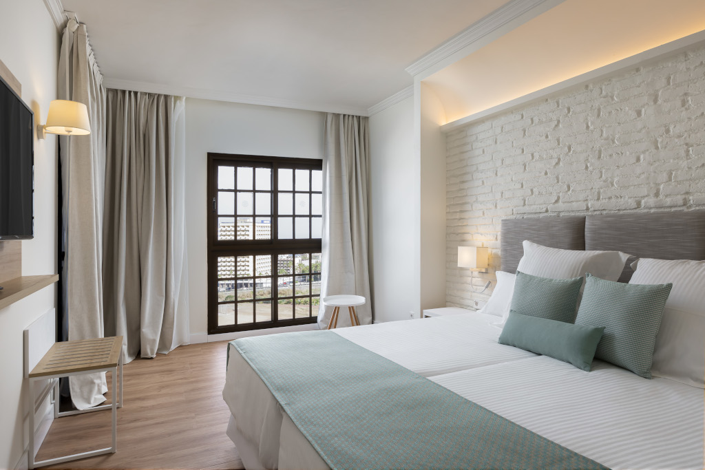 Camera da letto con letto matrimoniale, finestra e pareti bianche a Tenerife.