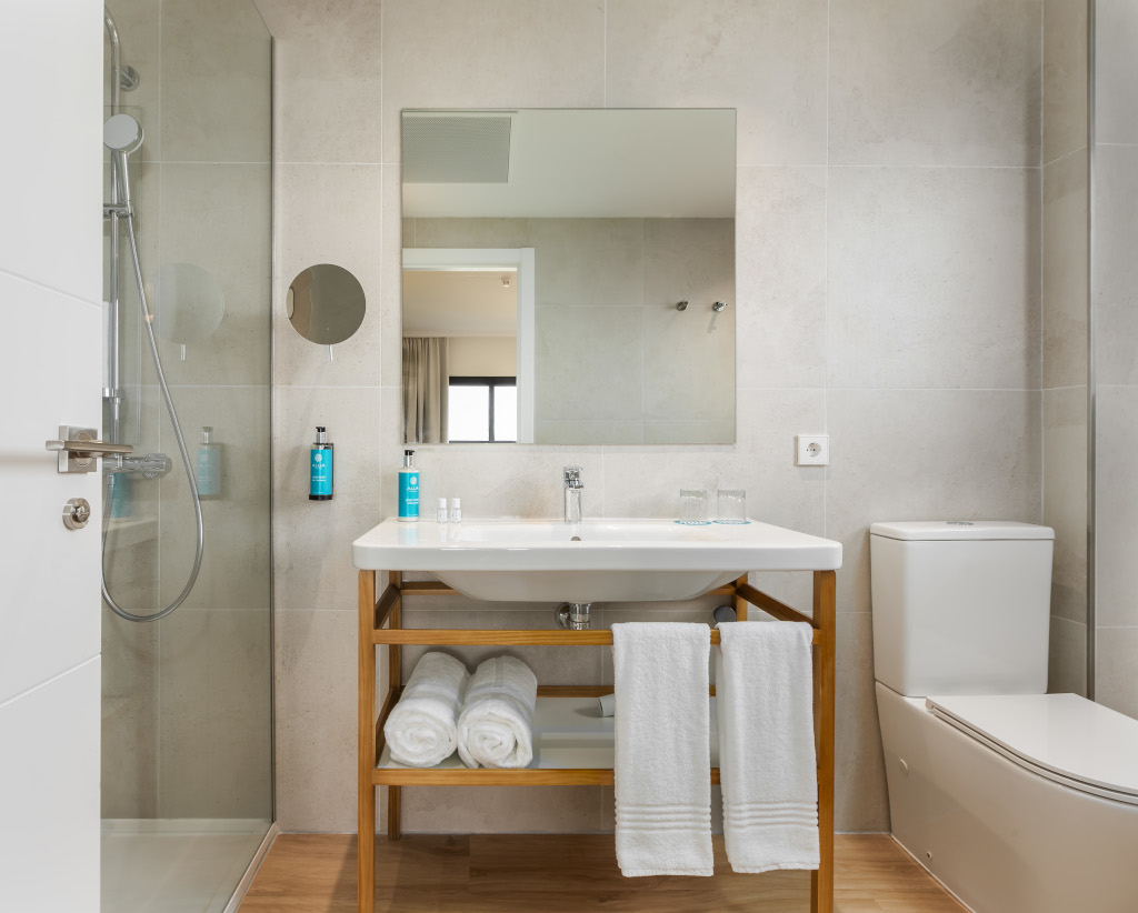 Bagno moderno con doccia, specchio e lavabo con asciugamani a Tenerife.