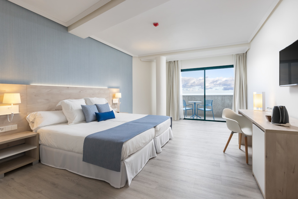 Camera d'albergo a Tenerife con letto, scrivania, balcone vista mare.