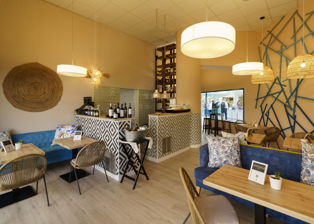 Interno di un moderno ristorante a Tenerife con tavoli apparecchiati e sedie in vimini.