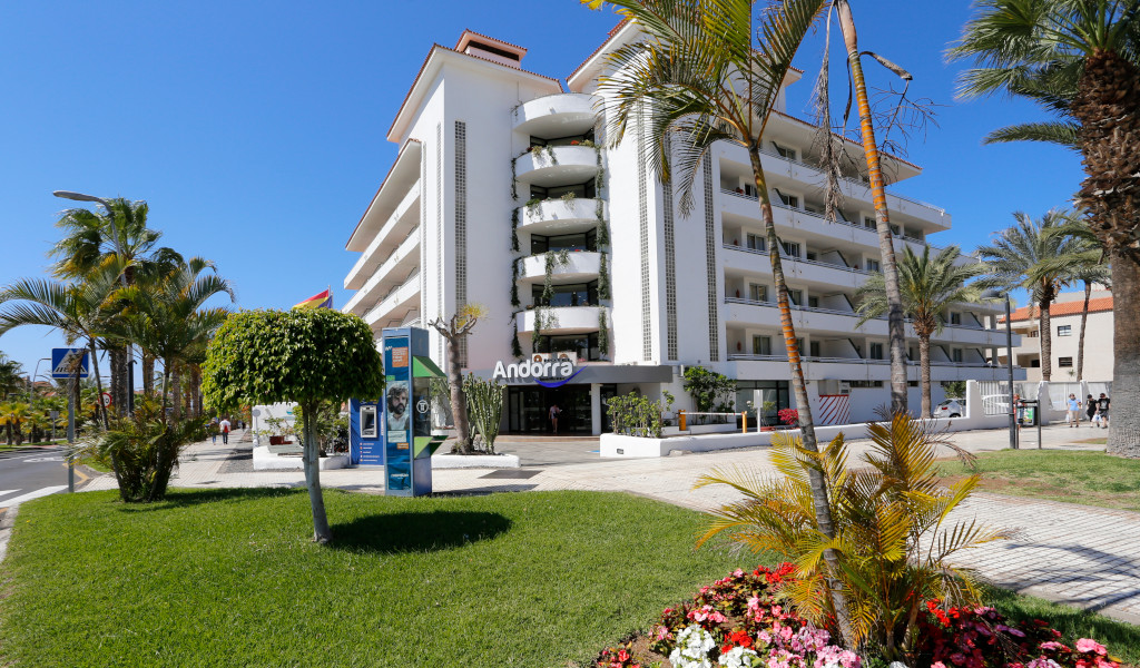 Edificio bianco con scritta Andorra a Tenerife, circondato da palme e fiori.
