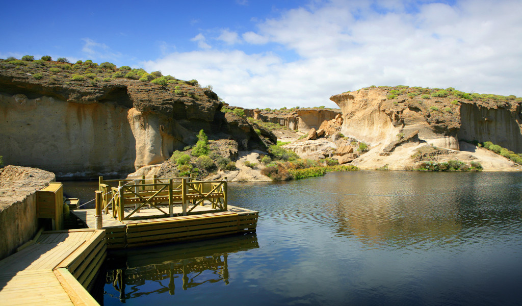 Passerella di legno sopra un lago con formazioni rocciose a Tenerife.