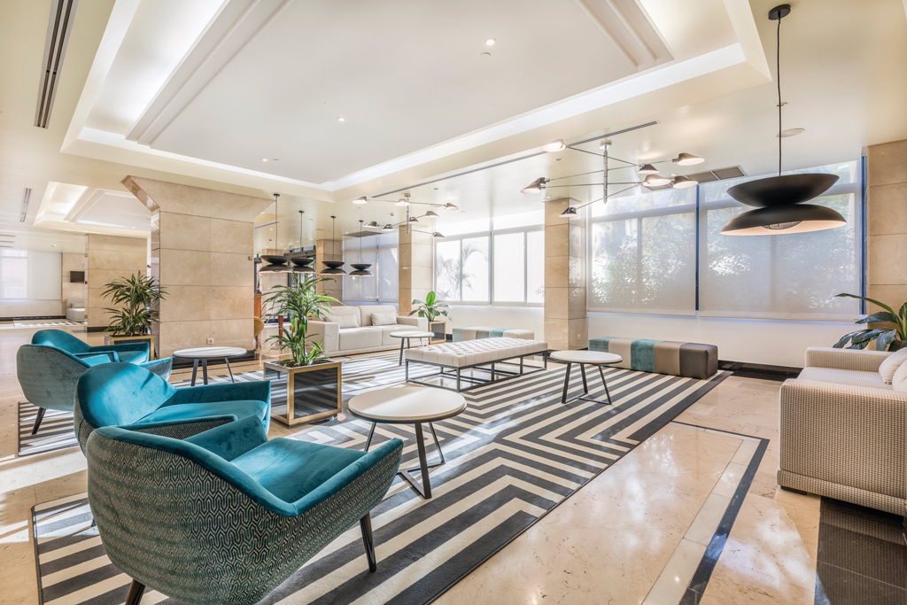 Ampia sala d'attesa con poltrone verdi, tavolini e piante a Santa Cruz de Tenerife.