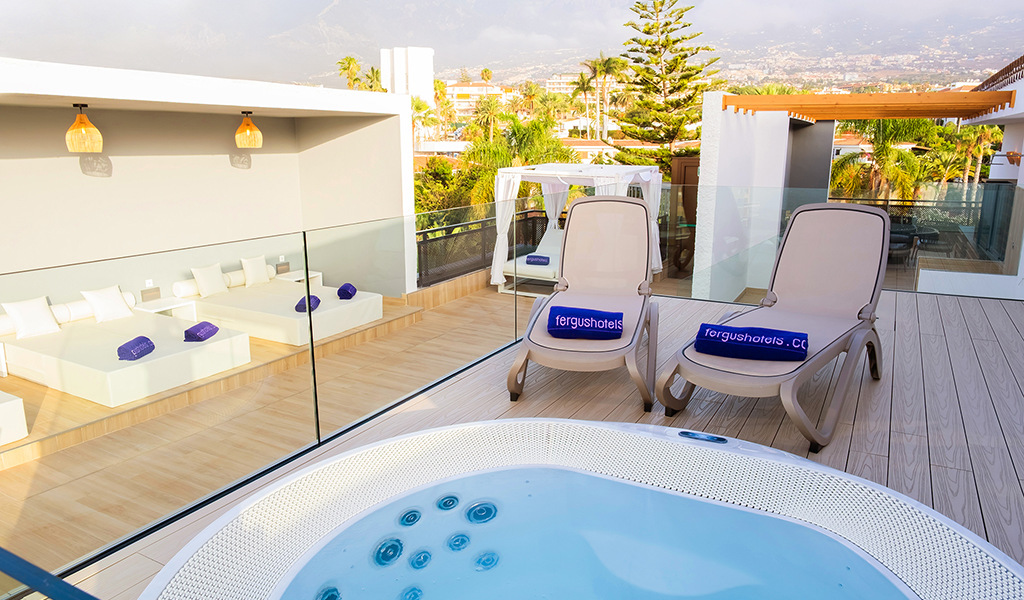 Terrazza con lettini e idromassaggio a Tenerife, vista su area verde.