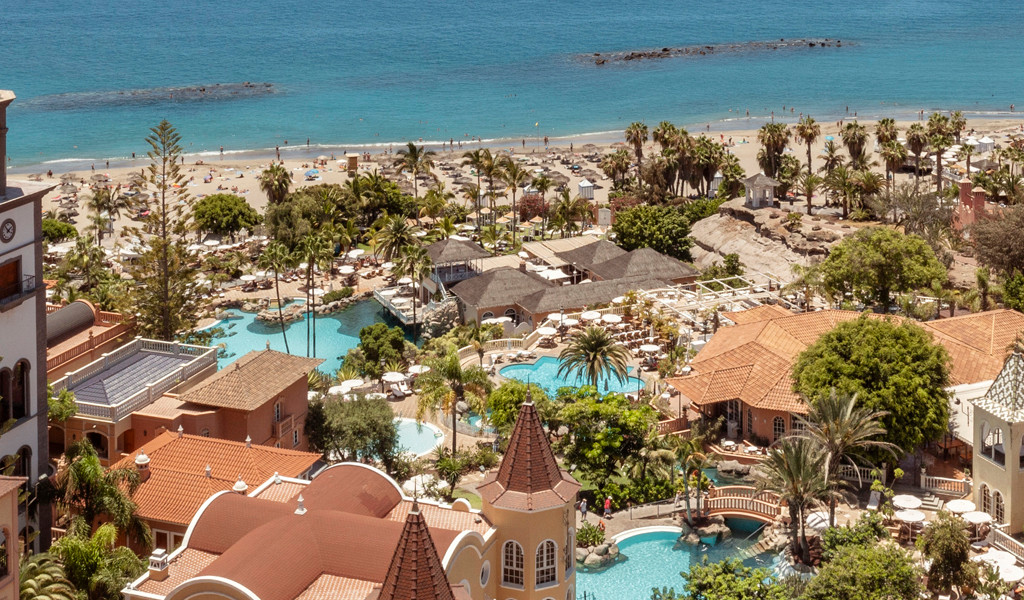 Località balneare a Tenerife con hotel, palme e vista oceano.