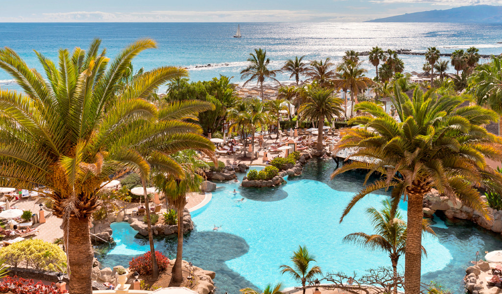 Piscina circondata da palme con vista mare a Costa Adeje, Tenerife.