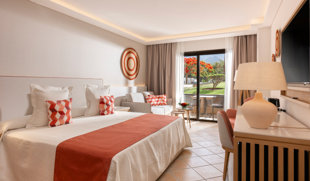 Camera d'albergo con vista sul giardino a Tenerife, letto matrimoniale e divano.