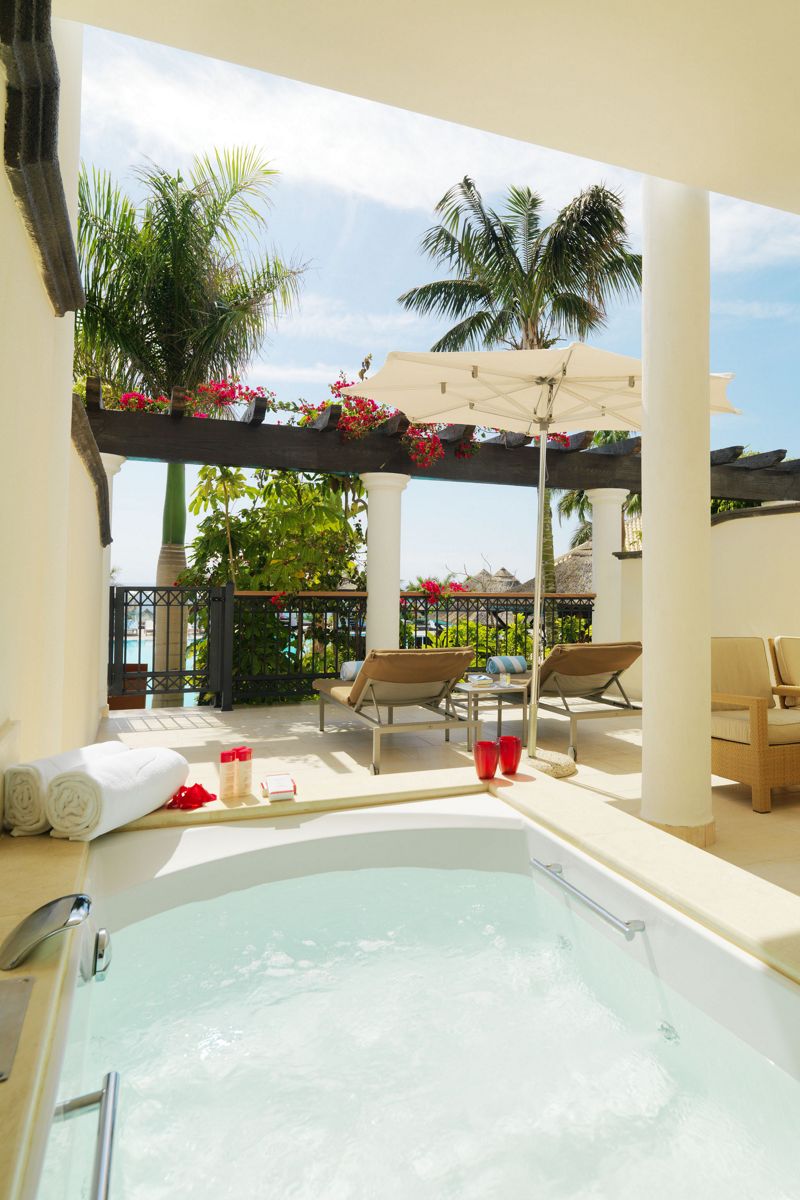 Terrazza con vasca idromassaggio, lettini e viste tropicali a Tenerife.